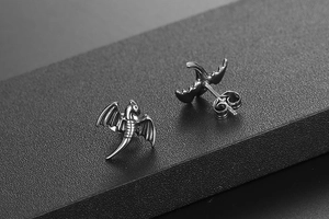 Gros plan de boucles d'oreilles dragon vintage en acier inoxydable avec ailes détaillées