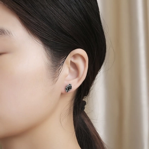 Macro detail of a vintage titanium steel earring with black stone on a model's ear
