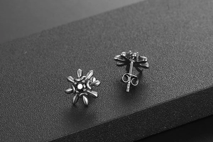 Macro side view of black sunflower stud earrings with dark zircon stones and butterfly backs