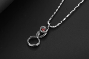Détail d'un pendentif serpent gothique avec pierre rouge sur une chaîne en argent vieilli