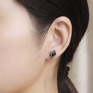 Close-up of titanium steel stud earring with black zircon and lava texture finish