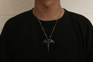Detail of dragon wings and sword pendant with unique two-tone silver and gold chain