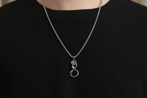 Gros plan du collier serpent rétro avec œil en zircon rouge sur un t-shirt noir