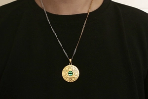 Close-up of titanium zodiac pendant with hexagram and inlaid green gemstone