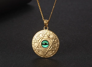 Detail of vintage gold constellation pendant with green stone and star embossing