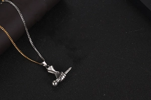 Détail d'un pendentif geste de main créatif avec une chaîne de collier bicolore