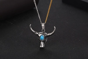 Détail macro du pendentif tête de bœuf vintage avec turquoise et chaîne en acier bicolore