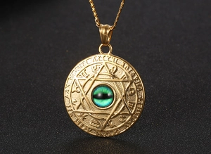 Macro shot of gold constellation pendant with green eye stone and mystic runes