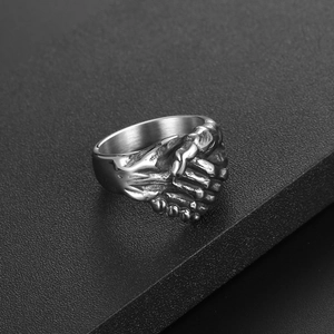 Bague vintage en acier inoxydable avec motif mains jointes sur support d'exposition noir