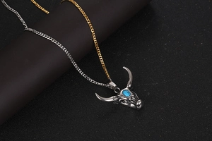 Détail d'un pendentif tête de yak vintage avec pierre bleue et chaîne bicolore
