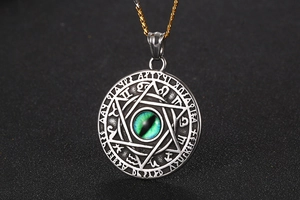 Macro view of vintage silver steel pendant with green eye stone and hexagonal carving
