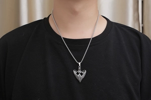 Détail du pendentif ailes d'ange rétro en acier titane sur un t-shirt noir homme