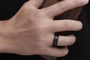 Detail shot of men's black titanium ring with dark snake skin texture and carbon fiber pattern