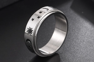 Macro shot of silver titanium spinning ring with engraved sun, moon and star patterns