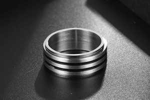 Gros plan sur bague en titane argenté avec texture brossée et rainures noires mates