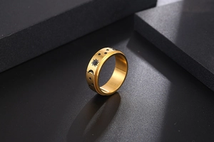 Macro detail of gold-plated wide band ring with embossed sun, moon and star patterns