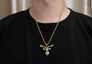 Close-up of golden stag head pendant with turquoise stone on a square link chain