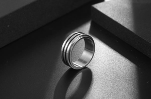 Détail d'une bague en acier titane brossé avec doubles rainures noires sur fond sombre