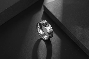 Détail macro d'une bague en acier titane avec nœud celtique et motifs tressés argent