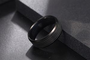 Macro shot of men's black titanium ring with knurled texture and polished edges