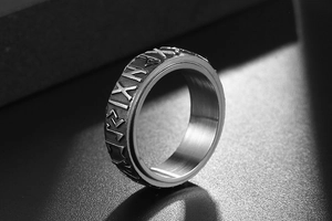 Close-up of Runic inscriptions on a brushed titanium steel ring with relief engraving