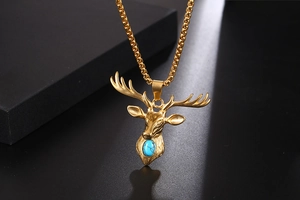Macro view of gold-tone deer head pendant with turquoise inlay and textured antlers