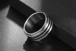 Vue macro d'une bague en acier titane brossé avec trois lignes noires parallèles