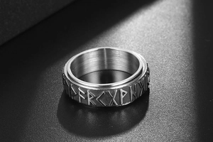 Macro detail of brushed stainless steel ring with engraved Viking runes and vintage finish
