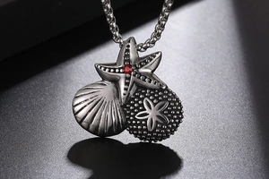 Macro detail of starfish and shell pendant with red rhinestone in vintage silver finish