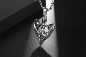 Gros plan du pendentif ange et démon en acier titane vintage avec ailes sur chaîne en métal