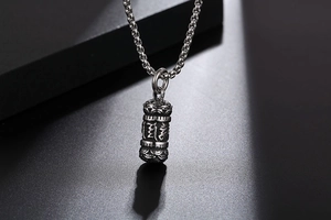 Macro detail of retro stainless steel lotus cylinder pendant with six-character mantra