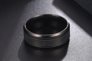 Macro shot of men's black titanium ring with industrial diamond grid texture pattern