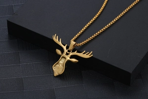 Close-up of golden stag head pendant with polished antlers and box chain on black box