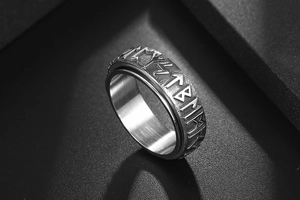 Macro shot of vintage stainless steel ring featuring engraved nordic runes on matte metal