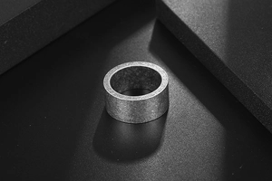 Detailed view of wide titanium steel band ring with retro matte grey finish and grainy texture