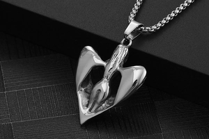 Détail macro du pendentif ailes d'ange en acier poli montrant la chaîne à mailles carrées