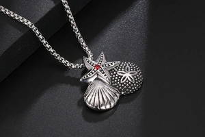 Detailed view of vintage titanium starfish and shell pendants with red gemstone on a box chain