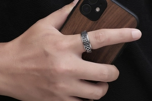 Macro detail of men's vintage titanium steel ring with engraved Nordic runes on finger