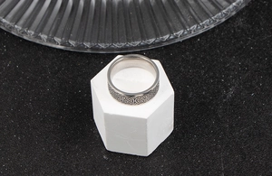 Macro detail of silver stainless steel ring with black Celtic knot textured pattern