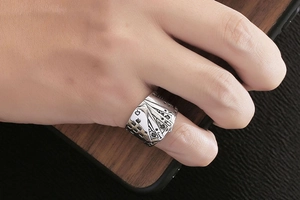 Detail of vintage silver titanium steel ring with poker card spade relief on male hand