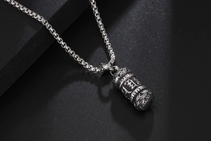 Detailed macro view of retro lotus mantra cylinder pendant in vintage titanium steel
