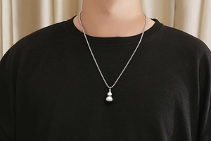 Detailed close-up of a silver polished gourd pendant on a titanium steel necklace for men