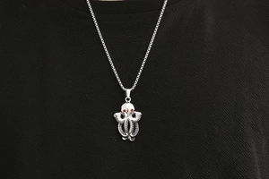 Detailed view of a vintage octopus pendant with red eyes on a stainless steel box chain
