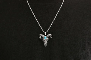 Detailed shot of retro bull head skull pendant with turquoise stone on steel chain