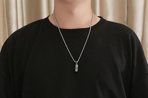 Close-up of vintage titanium steel necklace with engraved lotus mantra pendant on a male model