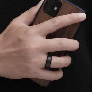 Men's titanium steel ring with black snakeskin texture and polished edges on hand