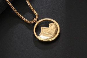Gros plan du pendentif montagne doré avec texture martelée et détail de la chaîne box