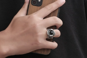 Detailed view of vintage silver twin snake ring with black onyx bead on male hand