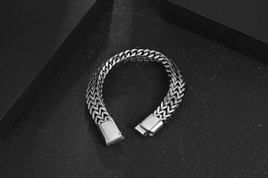 Détail d'un bracelet tressé en acier titane argenté avec chaîne épaisse et fermoir rectangulaire