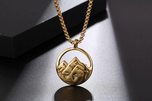 Détail macro d'un collier en acier titane doré avec un pendentif texturé de montagne